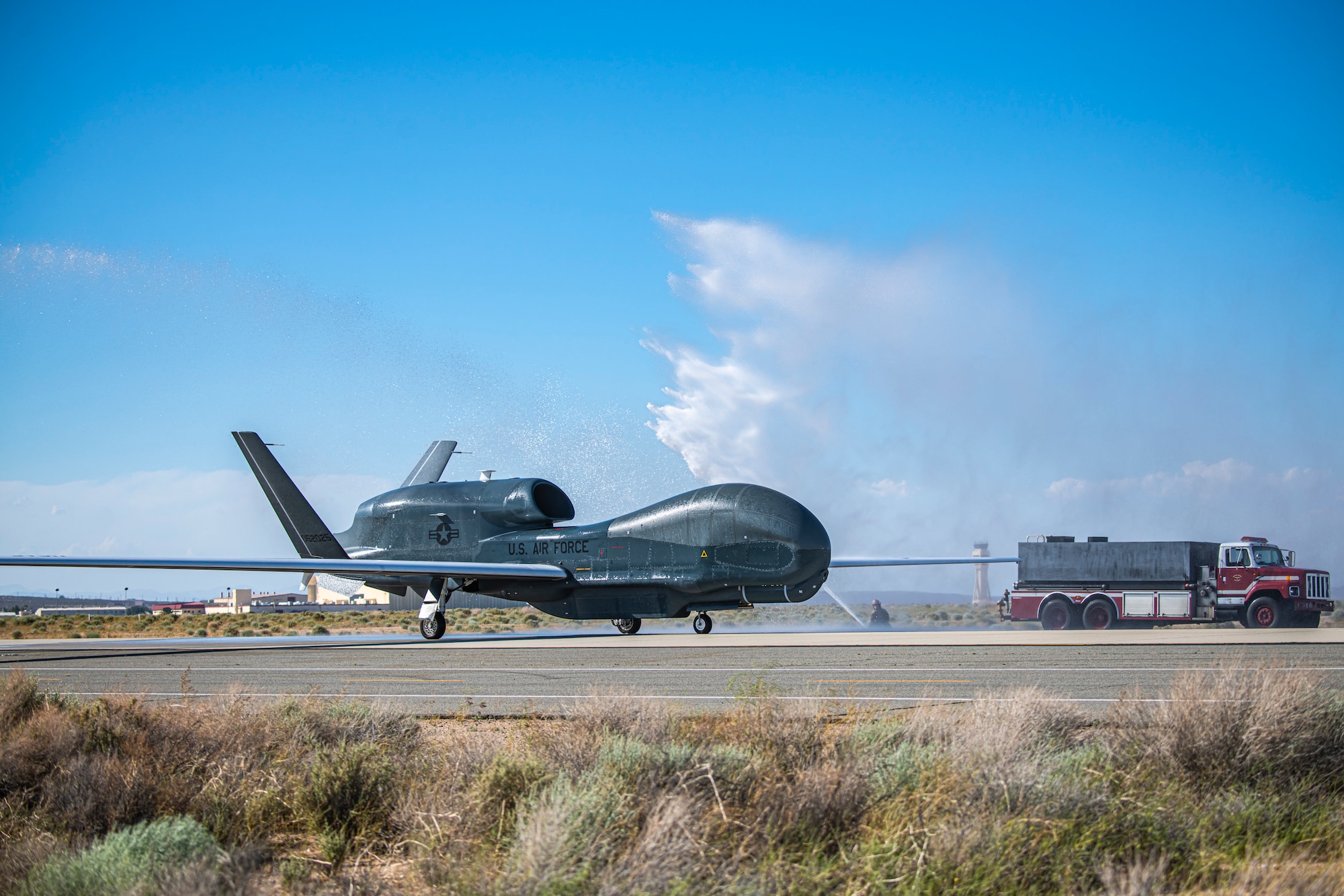 Fire trucks from the 812th Civil Engineer Squadron provide a water salute to an RQ-4 Global Hawk, assigned to and operated  by the 452nd Flight Test Squadron, at Edwards Air Force Base, California, May 23. The 452nd FLTS held a “sunsetting” event for the RQ-4 Global Hawk flight test program at Edwards AFB, June 9. The event marked the completion of the squadron’s test campaign for the aircraft. (Air Force photo by Giancarlo Casem)