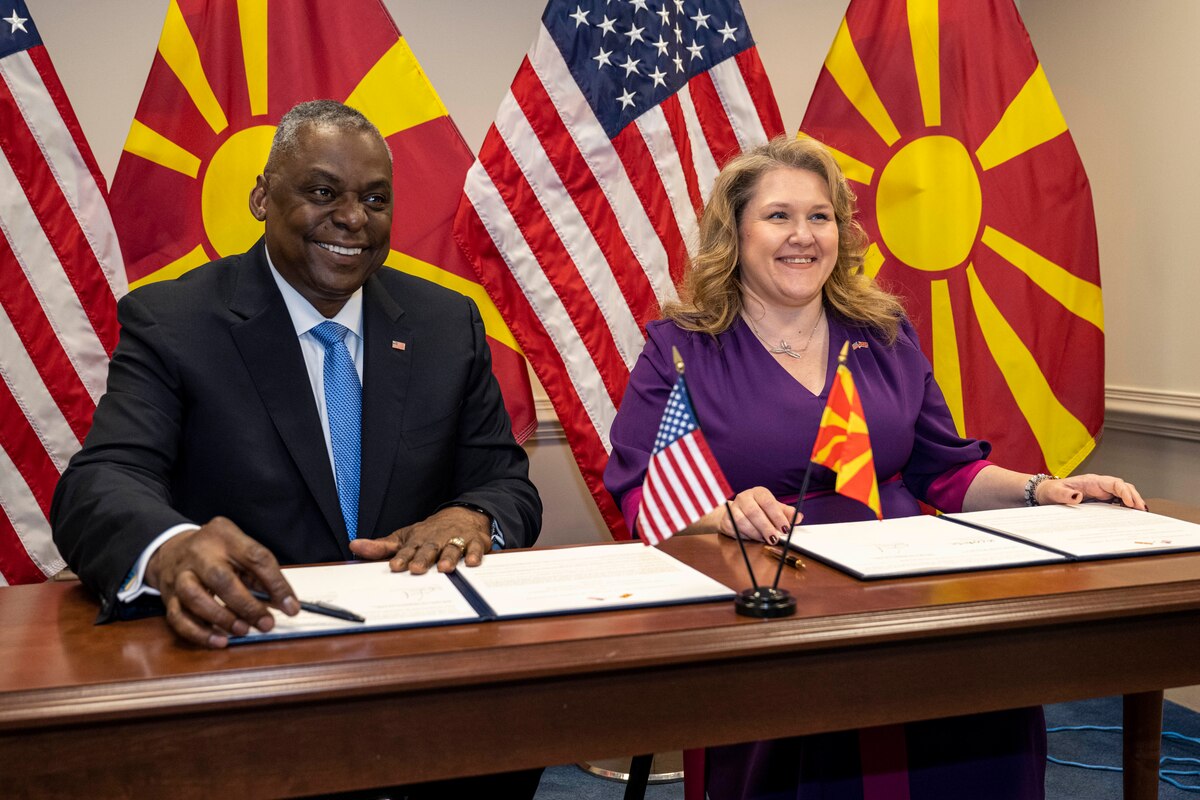 A man and woman sit are photographed sitting behind a table.