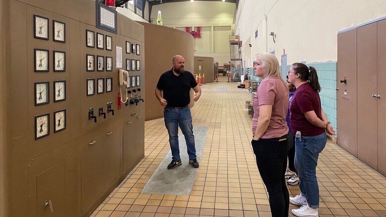 Man stands with two visible teachers in front of power unit.