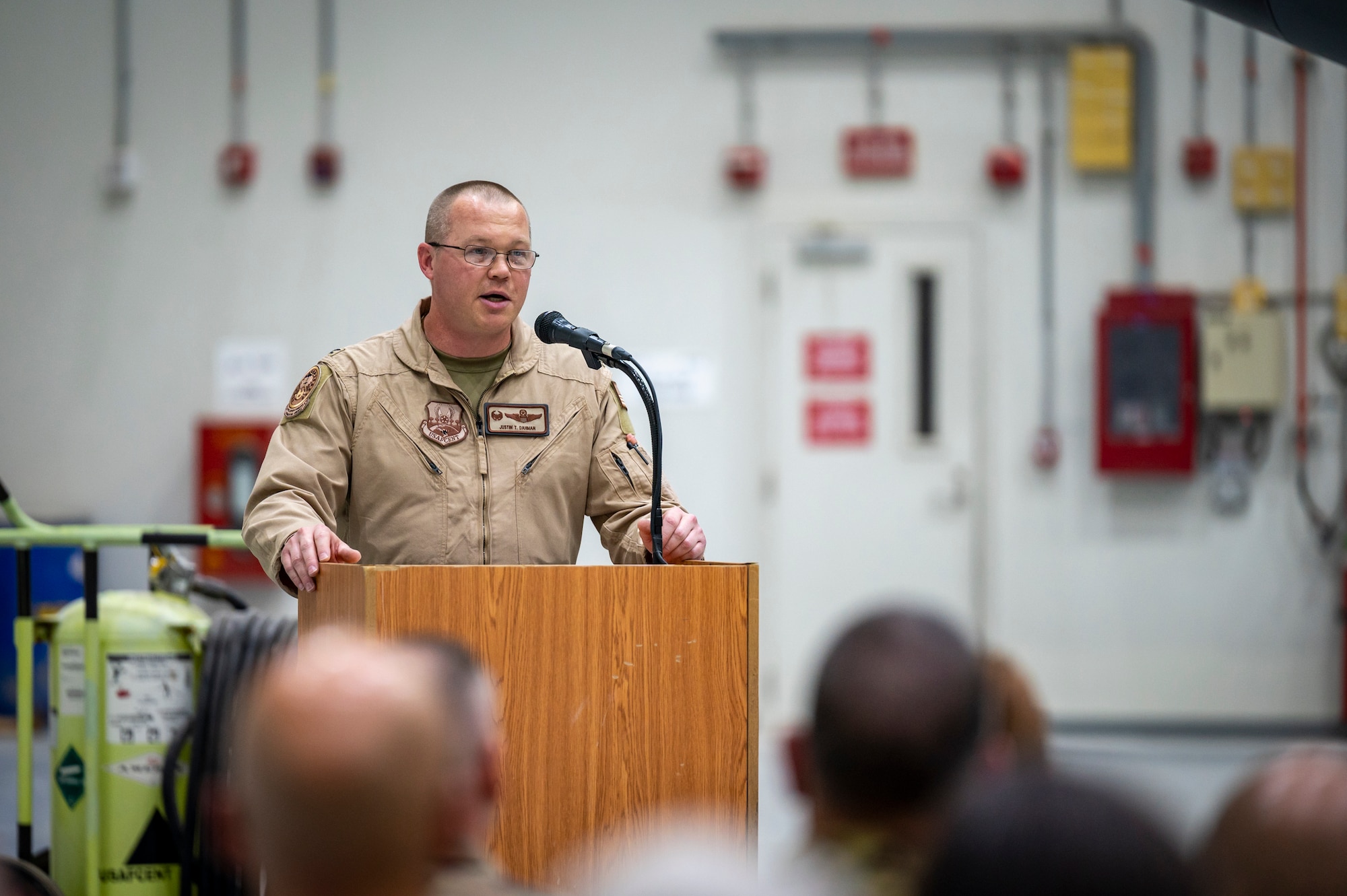 A military member stands at a podium and gives a speech to a crowd of people.