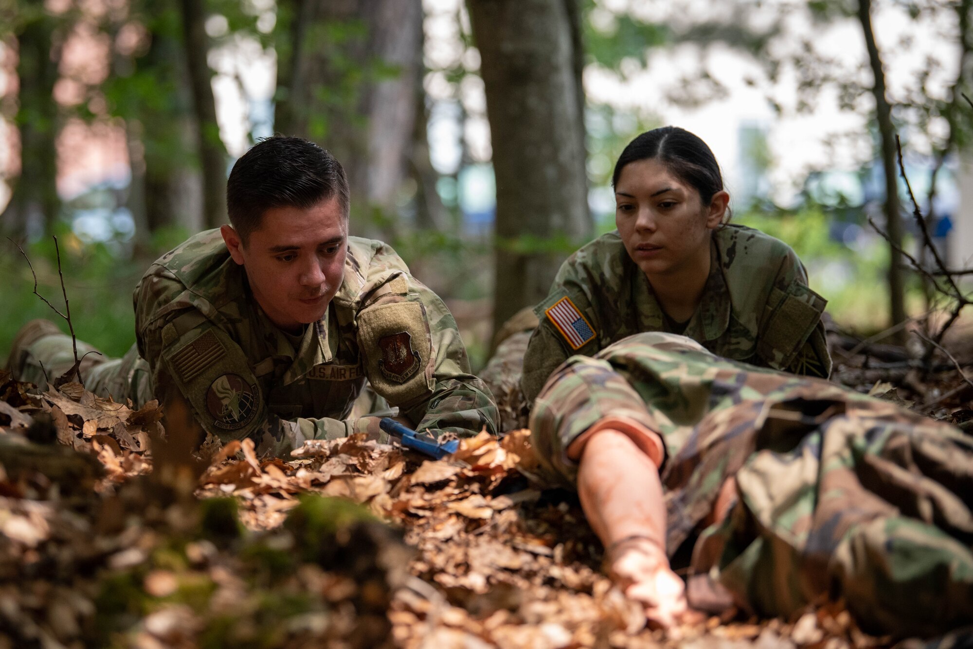 U.S. Army Staff Sgt. Karla Neria, 16th Sustainment Brigade mortuary affairs non-commissioned officer (right), and U.S. Air Force Senior Airman Lucas King, 786th Force Support Squadron fitness center specialist (left), assess the condition of simulated remains and disarm a mock improvised explosive device during a search and recovery exercise at Ramstein Air Base, Germany.