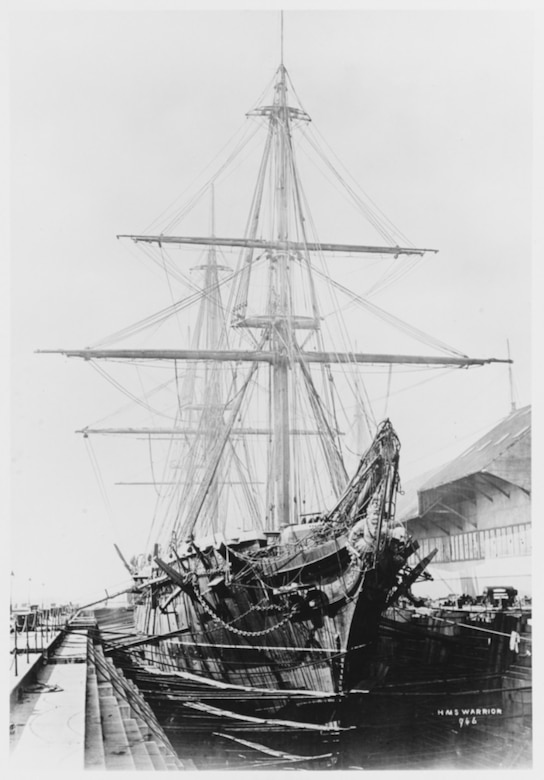 HMS Warrior in drydock at Portsmouth, toward the end of her 1872-75 refit. Note the newly-fitted longer bowsprit, with her warrior figurehead below. U.S. Naval History and Heritage Command Photograph.