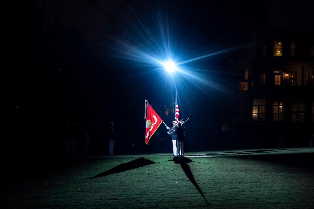 Service members present flags during a nighttime parade.