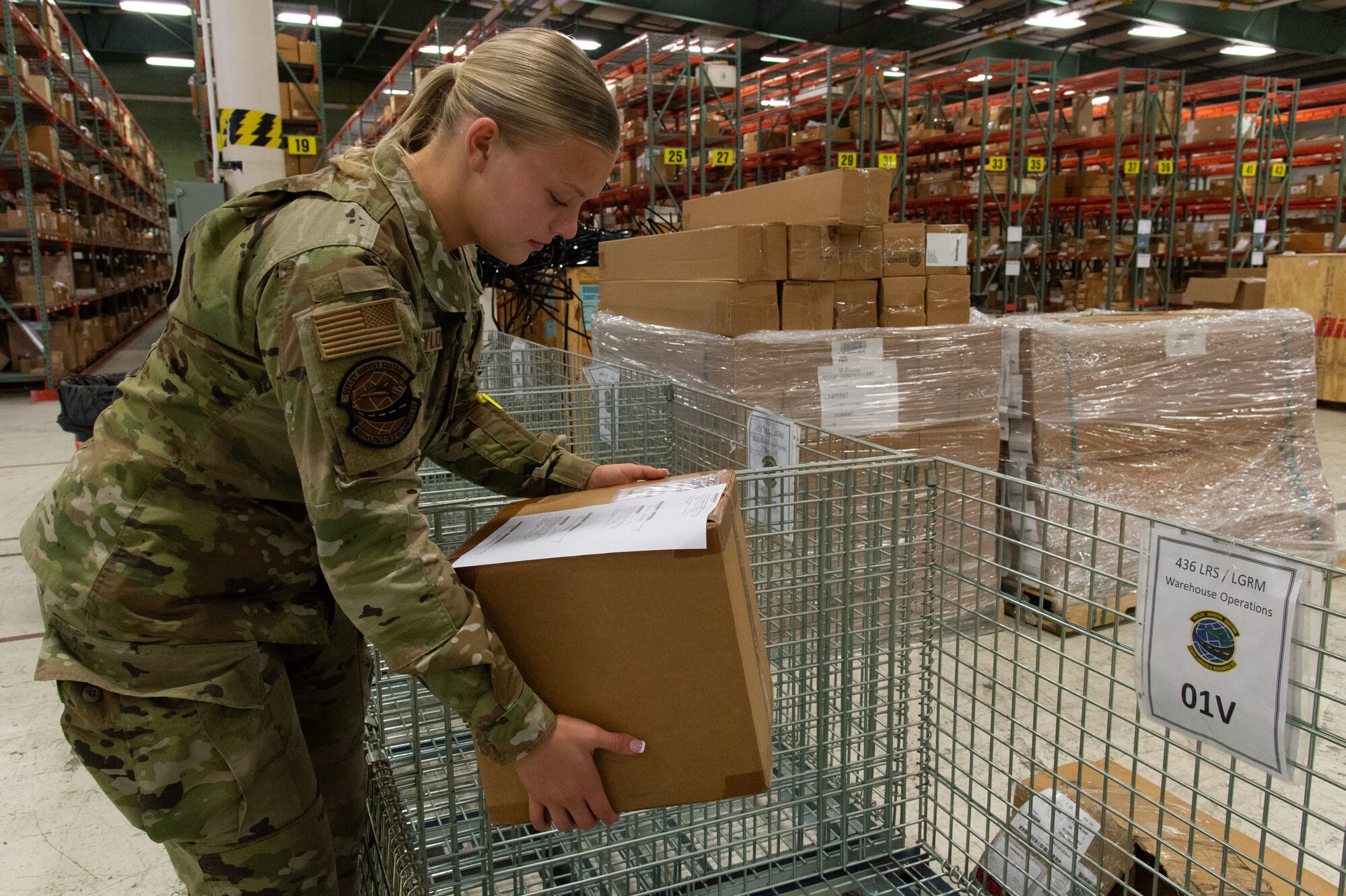 Airman Zoey Baylor, 436th Logistics Readiness Squadron central storage apprentice, picks up a package containing an aircraft part ready to be stored in the supply warehouse at Dover Air Force Base, Delaware, May 11, 2023. Personnel from the 436th Aerial Port Squadron Traffic Management Office (inbound) place processed items in marked cages letting central storage personnel identifying items ready to be placed in the warehouse. (U.S. Air Force photo by Roland Balik)