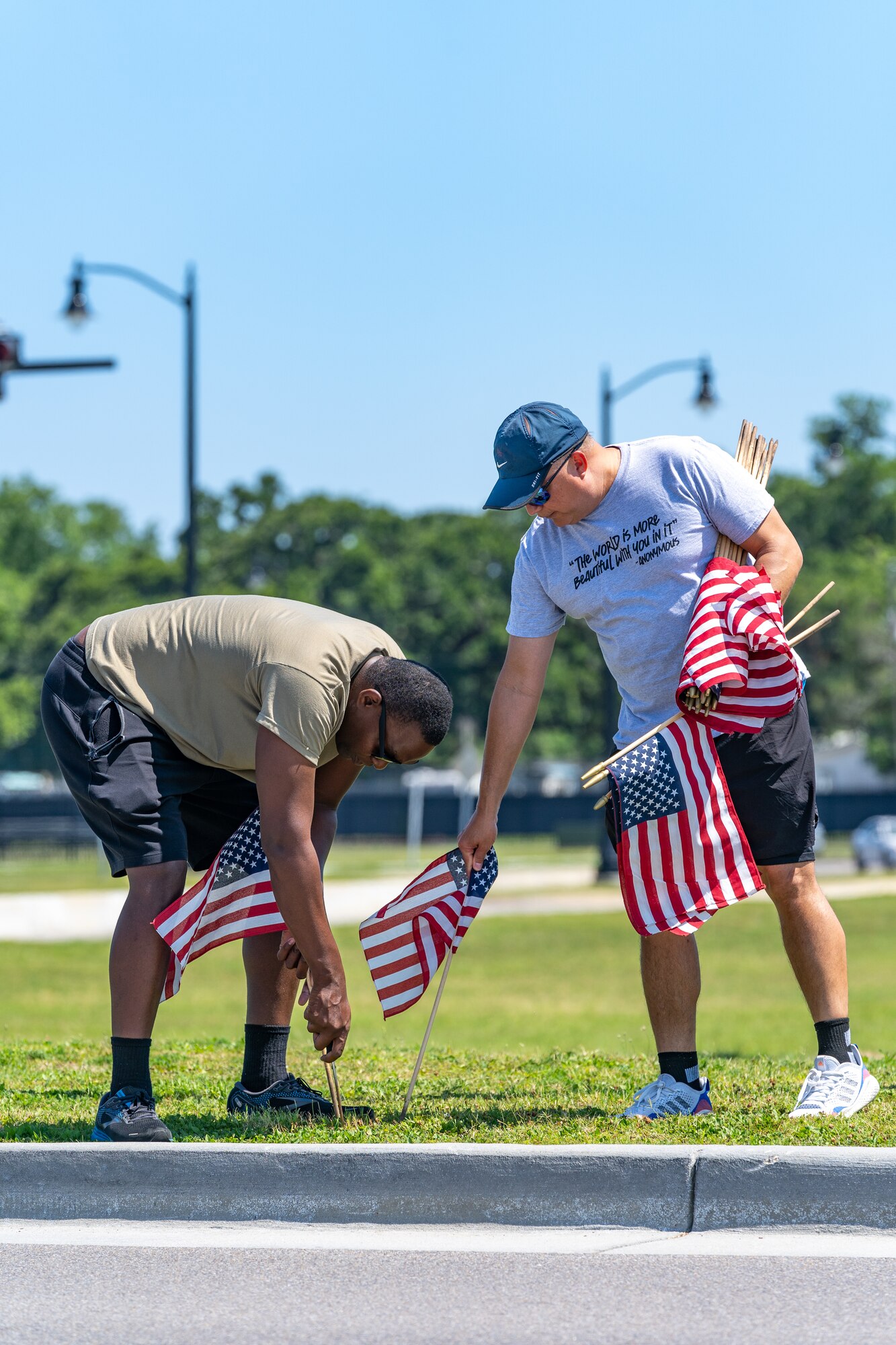 U.S. Air Force Senior Airman Darren Perry, 85th Engineering Installation Squadron cable and antenna systems, and Dan Kazumura, Air Force Sergeants Association chapter 652 president, place flags at Keesler Air Force Base, Mississippi, June 12, 2023.