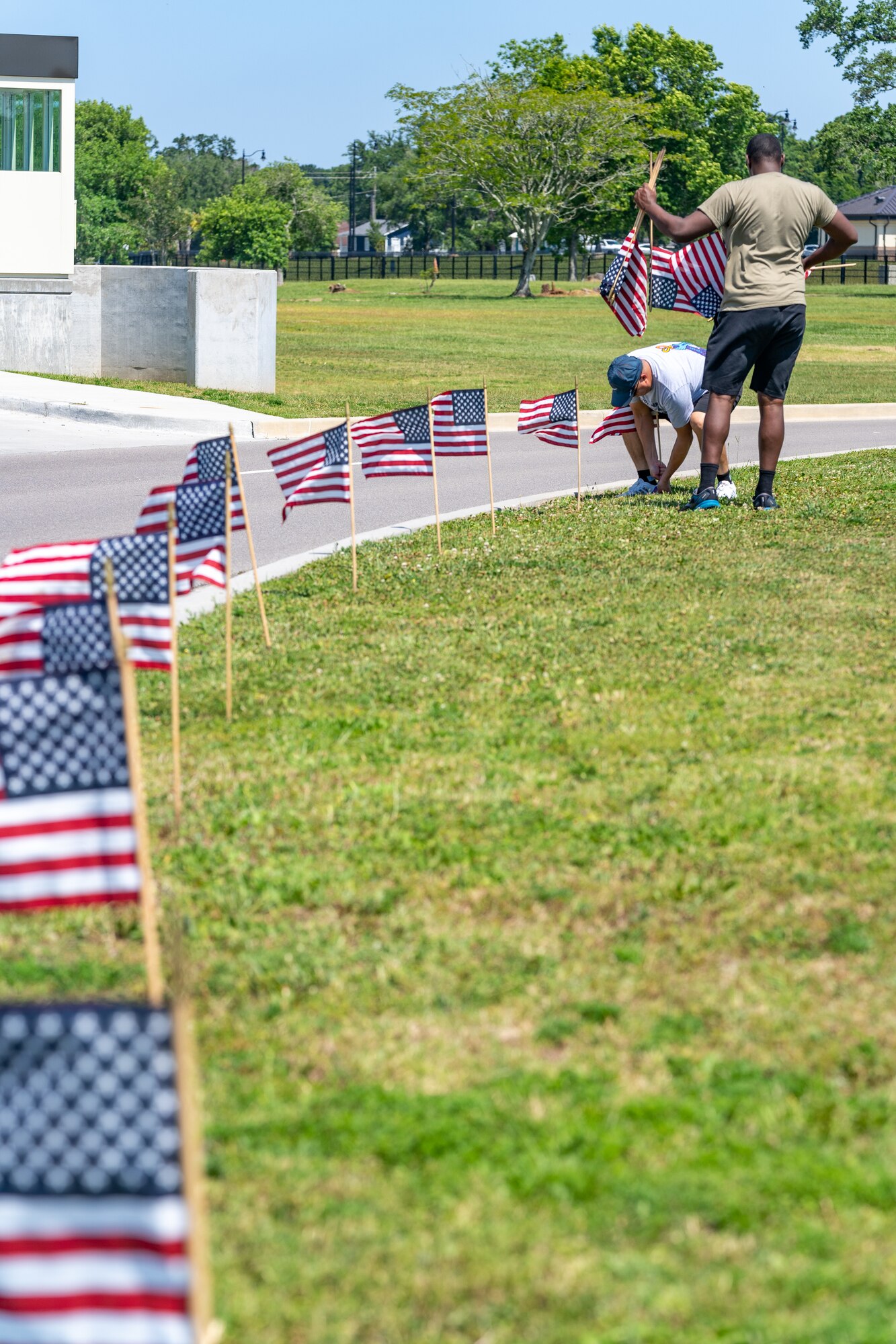 U.S. Air Force Senior Airman Darren Perry, 85th Engineering Installation Squadron cable and antenna systems, and Dan Kazumura, Air Force Sergeants Association chapter 652 president, place flags at Keesler Air Force Base, Mississippi, June 12, 2023.