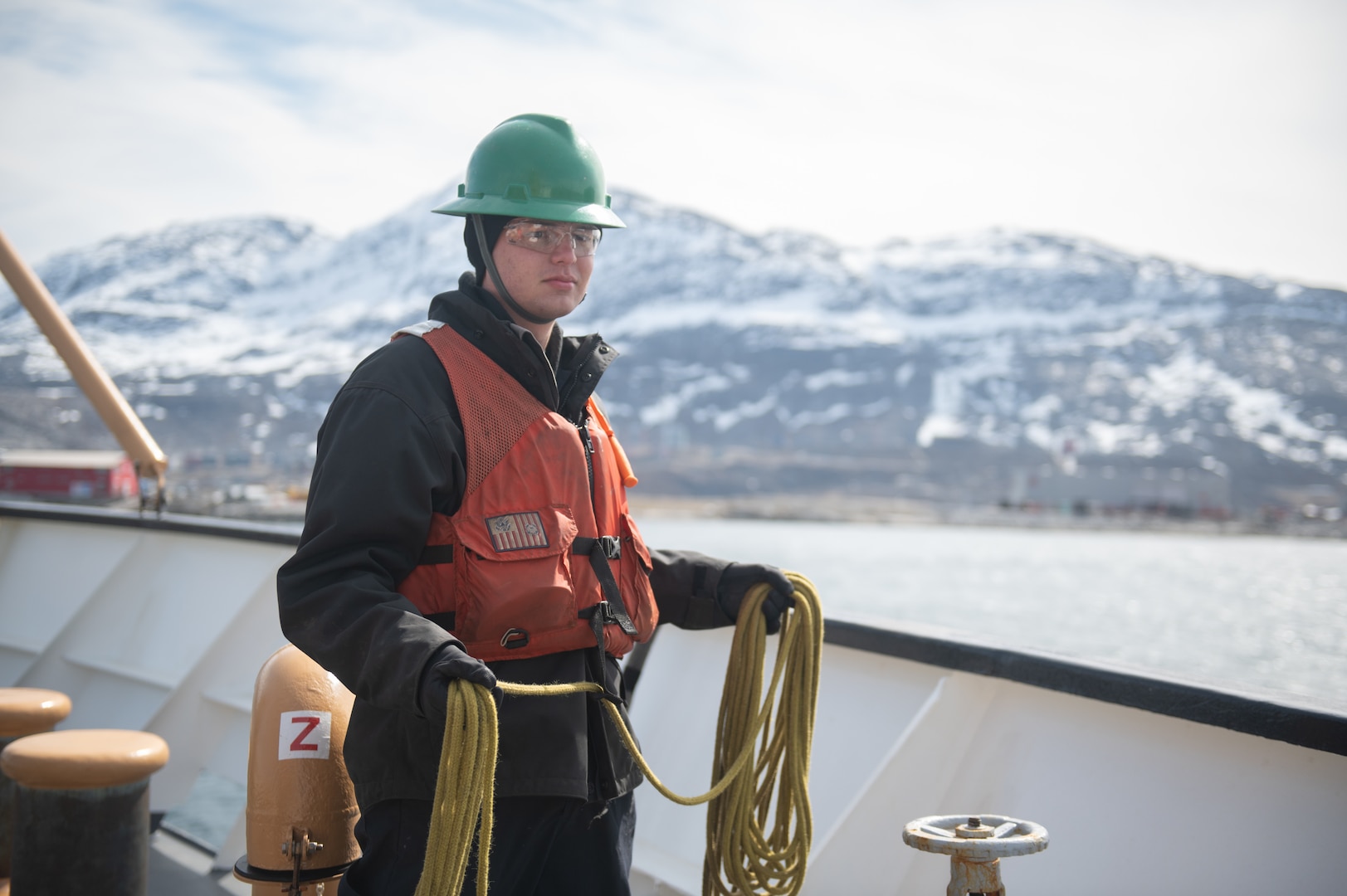 U.S. Coast Guard Seaman Griffin Peterson, a crewmember aboard USCGC Sycamore (WLB 209), prepares to throw a heaving line while mooring in Nuuk, Greenland, June 10, 2023. Sycamore is participating in Exercise Argus, a joint search and rescue and marine environmental response exercise that includes assets from the United States, Denmark, Greenland, and France. (U.S. Coast Guard photo by Petty Officer 2nd Class Ryan Schultz)