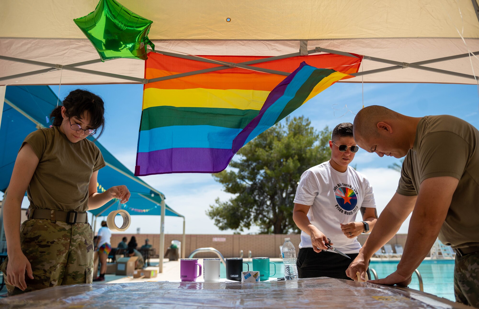 U.S. Air Force Airman 1st Class Ysabella Paris, Master Sgt. Melissa Lord, and Tech. Sgt. Oliver Ocampo, 56th Component Maintenance Squadron personnel, build a cardboard boat during a Pride Month event hosted by the Luke Pride Committee, June 9, 2023, at Luke AFB, Arizona.