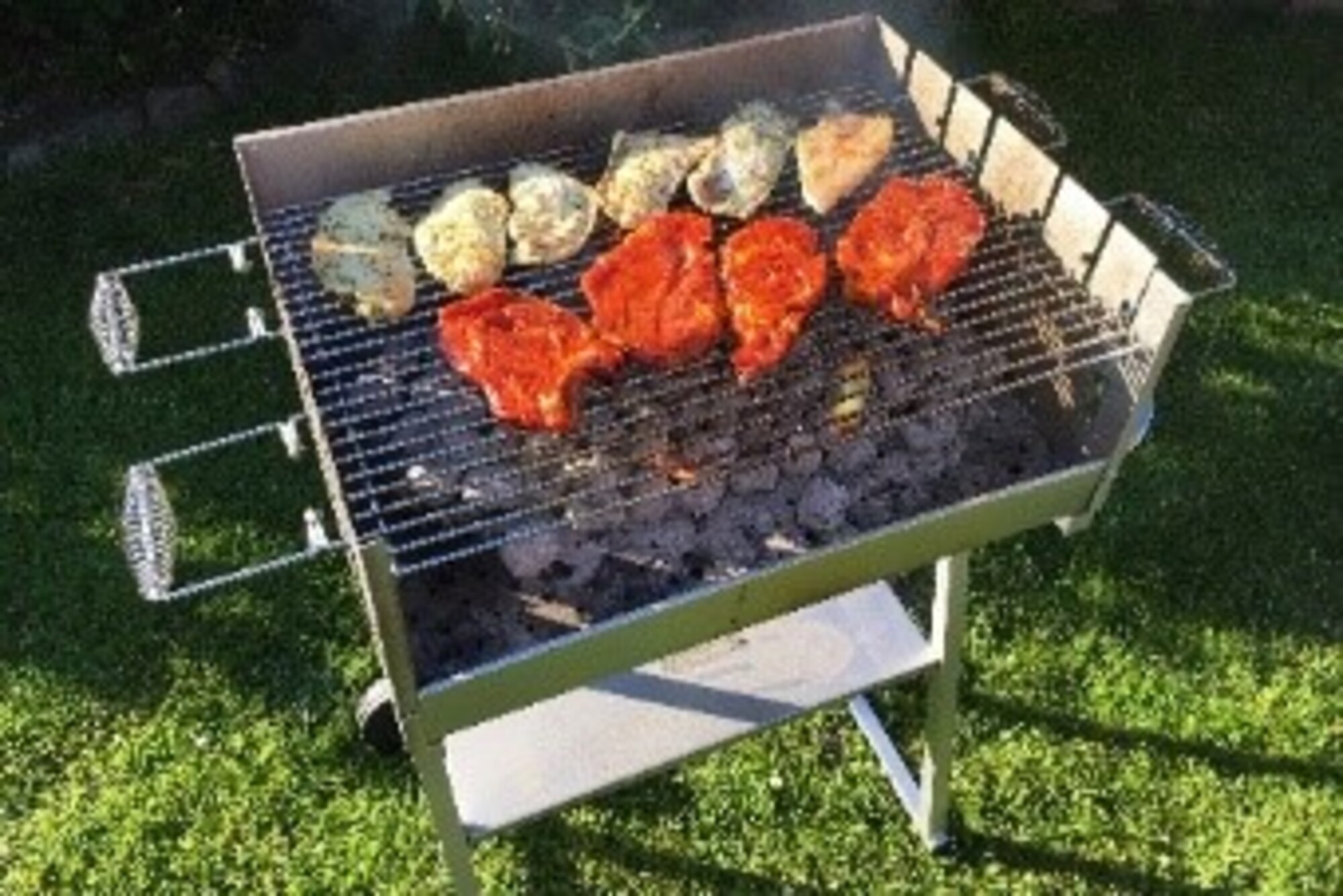 A photo of a grill with meat cooking.