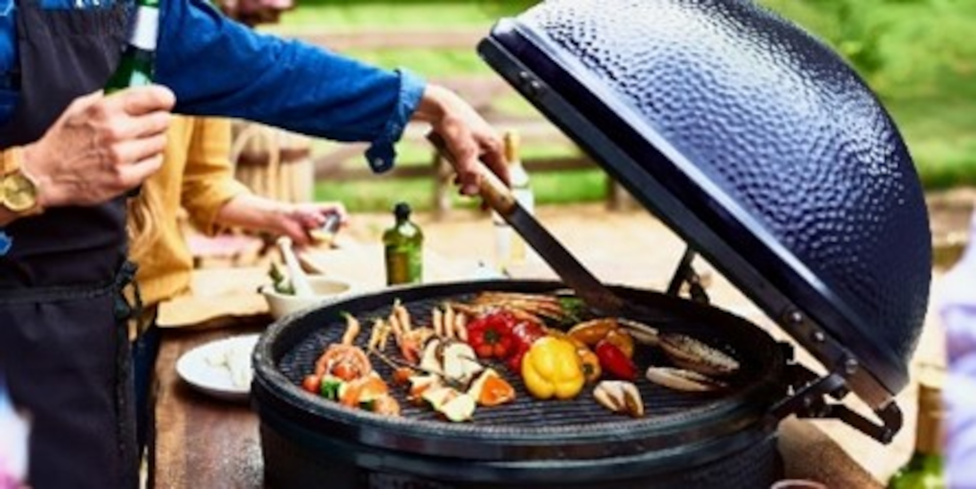 A photo of a person grilling some vegetables and meat.