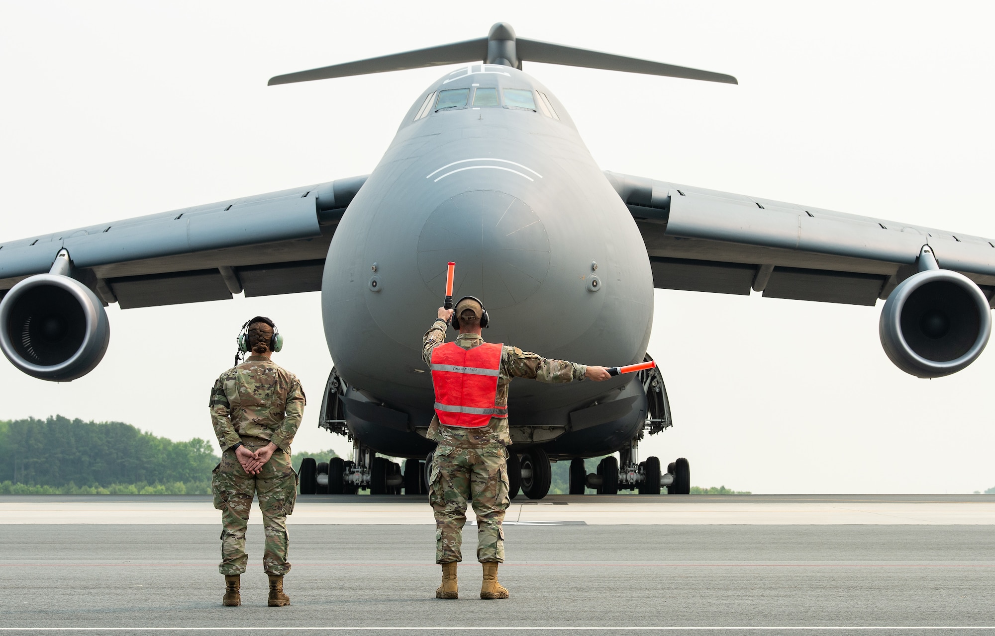 Capt. Kris Eddy, center, 436th Aircraft Maintenance Squadron aircraft maintenance unit officer in charge, marshals a C-5M Super Galaxy off its parking spot at Dover Air Force Base, Delaware, June 6, 2023. Airman 1st Class Sierra Davenport, left, 436th AMXS crew chief, provides Eddy with marshaling instructions as the aircraft moves towards them. The Super Galaxy was the second of seven to depart Dover AFB during the base’s hurricane evacuation exercise. (U.S. Air Force photo by Roland Balik)
