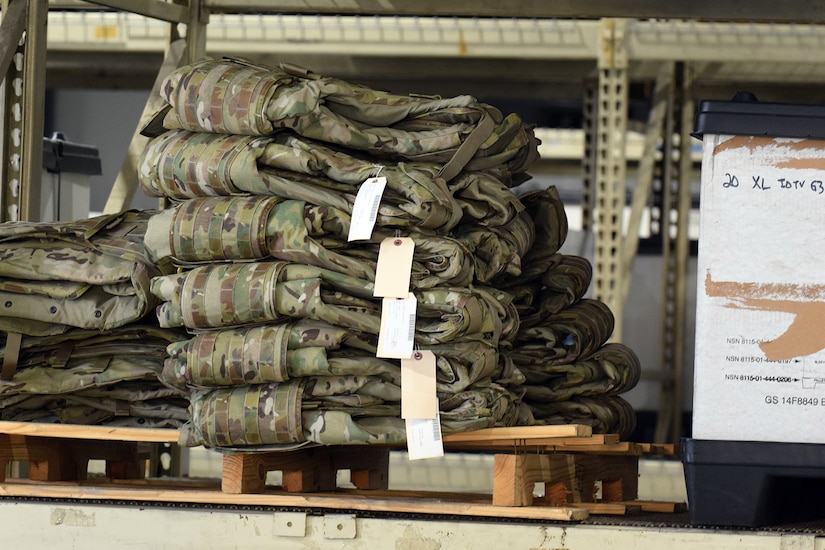 Several pallets, containing military vests, sit next to each other.
