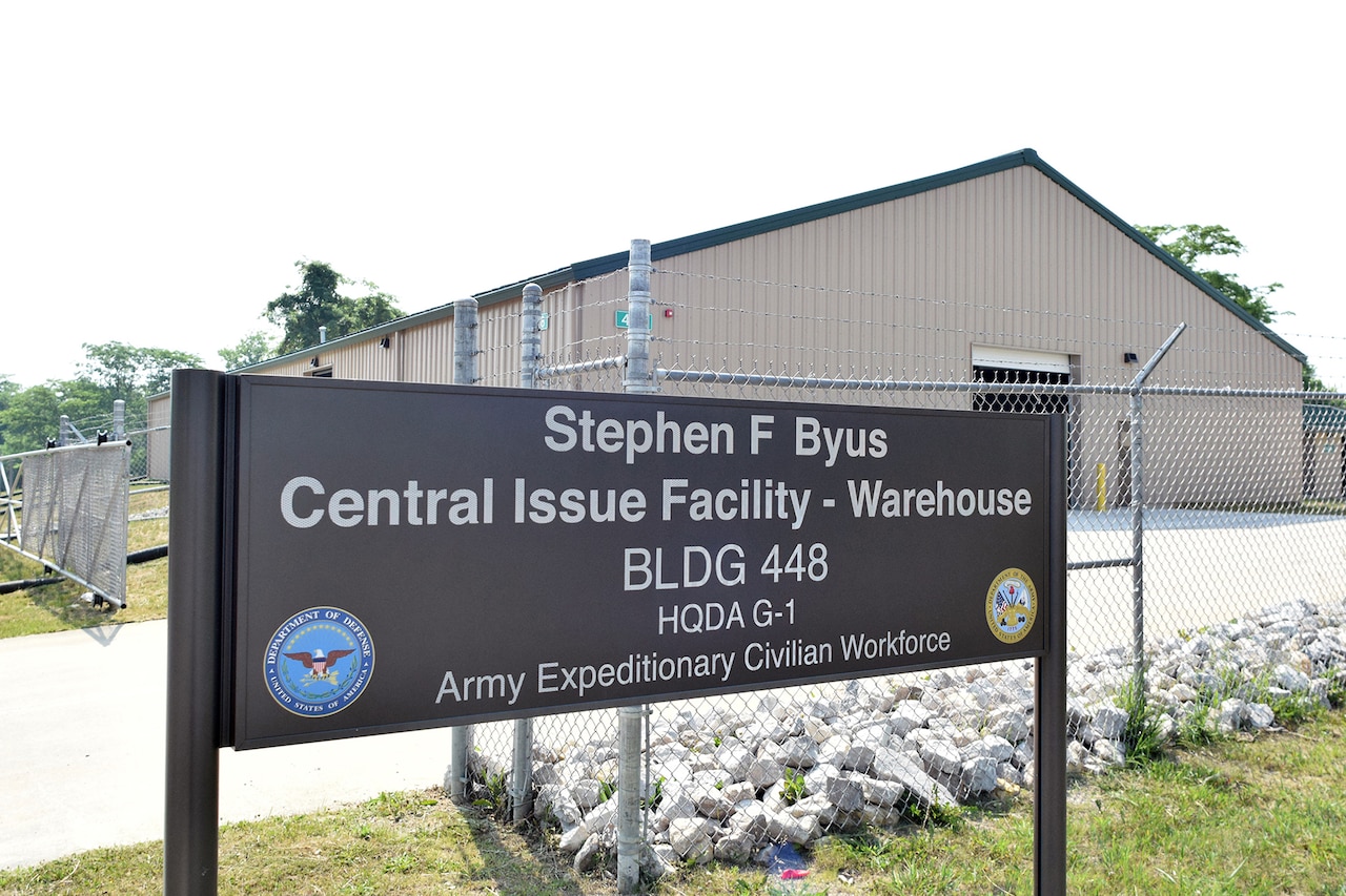 A sign in front of a gated warehouse indicates that this is the Stephen F. Byus warehouse.