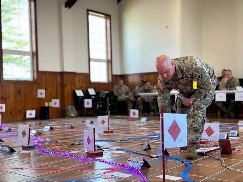 A Soldier from the New York National Guard's 42nd Infantry Division marks a spot on a floor map May 29, 2023, at Fort Indiantown Gap, Pa., during a combined arms rehearsal prior to a Warfighter exercise. (This photo was altered to obscure an ID card) (Photo courtesy of the 1st Armored Division)