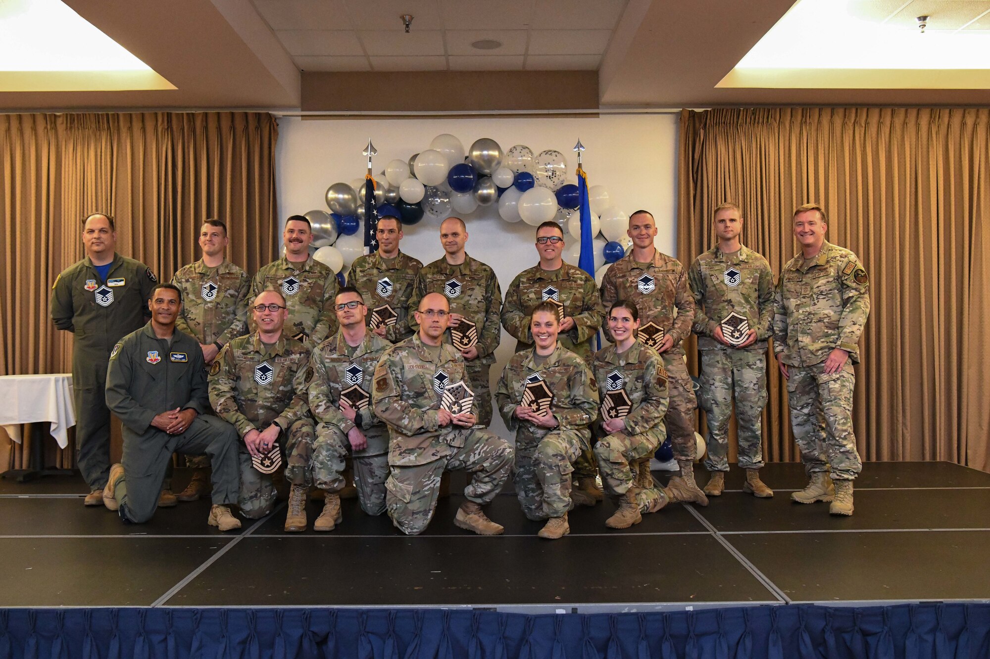 Fifteen men and women in green military uniforms pose for a photo.