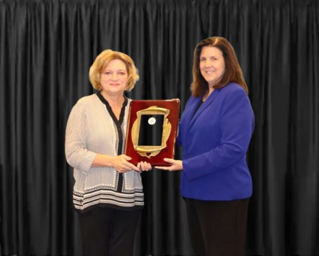 two women pose with award plaque