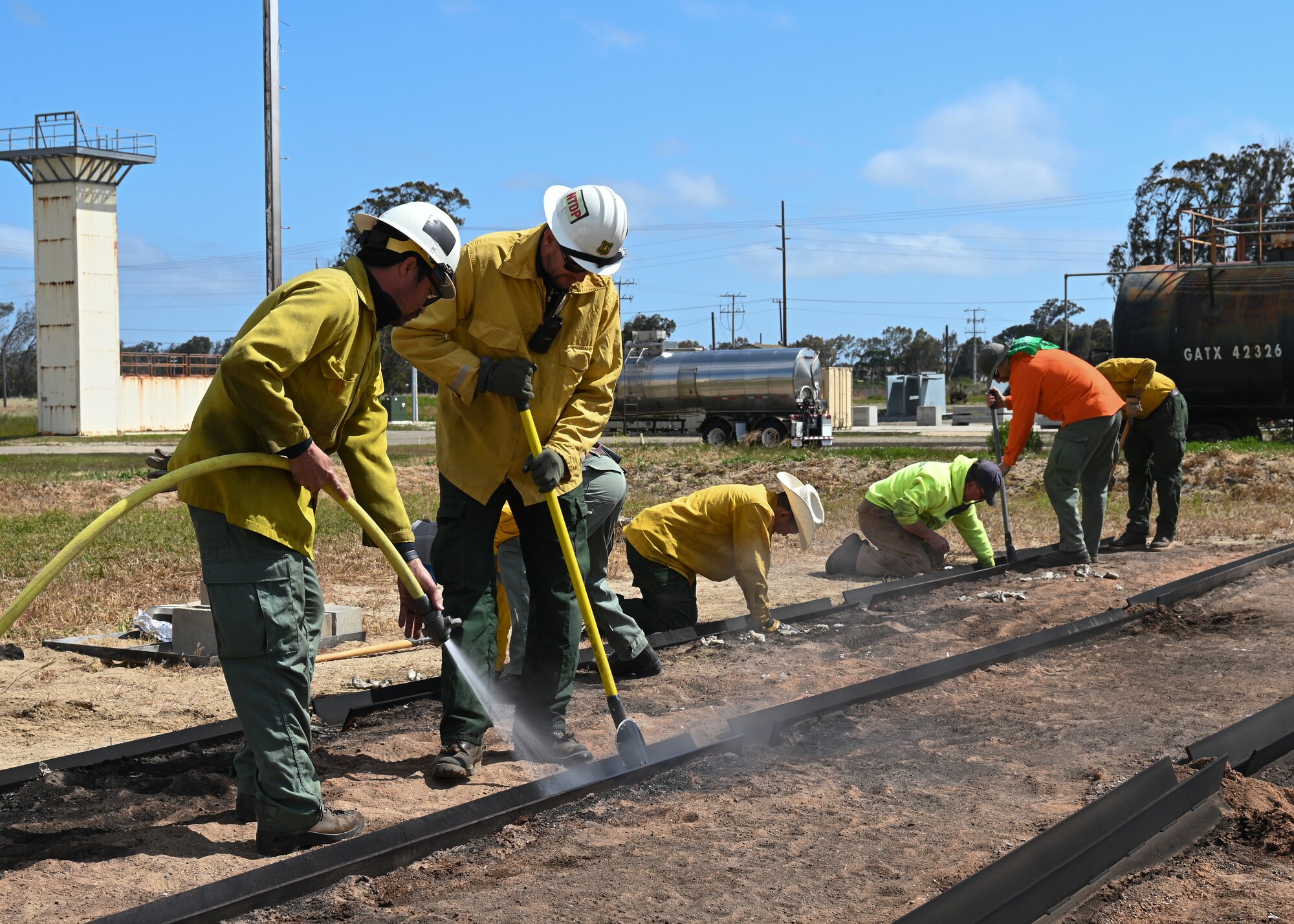 Technicians from the U.S. Forest Service National Technology and Development Program extinguish a test burn at Vandenberg Space Force Base, Calif., May 11, 2023. The crew used a fire front simulator system to replicate the various stages of a wildfire, including the approach, immersion, and post-radiation phases. The purpose of these tests was to gather essential data on how heat exposure impacts both equipment and personnel. (U.S. Space Force photo by Senior Airman Tiarra Sibley)
