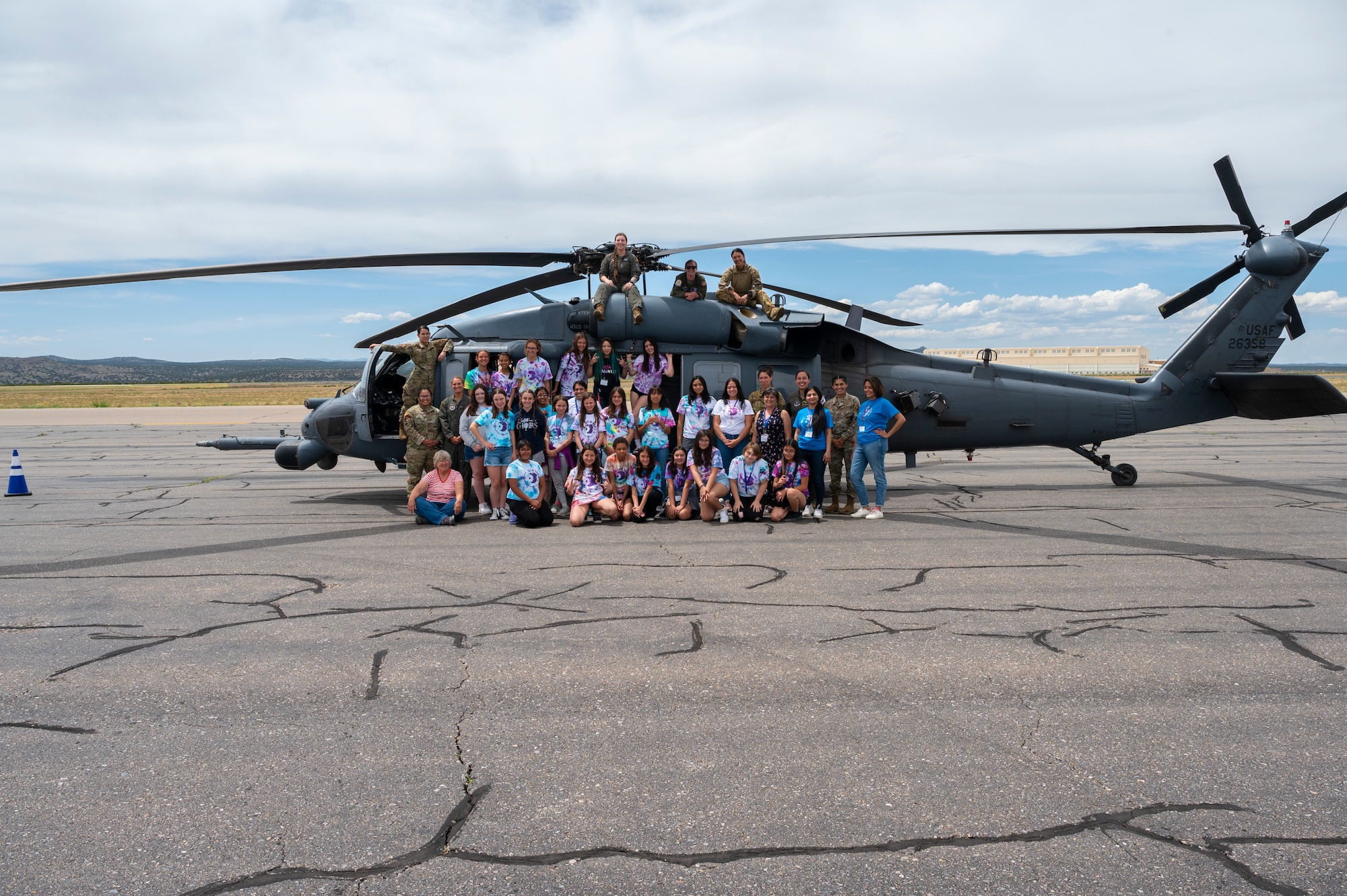 A group poses in front of a helicopter.