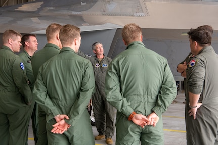 pilots talking around F-22 in hangar