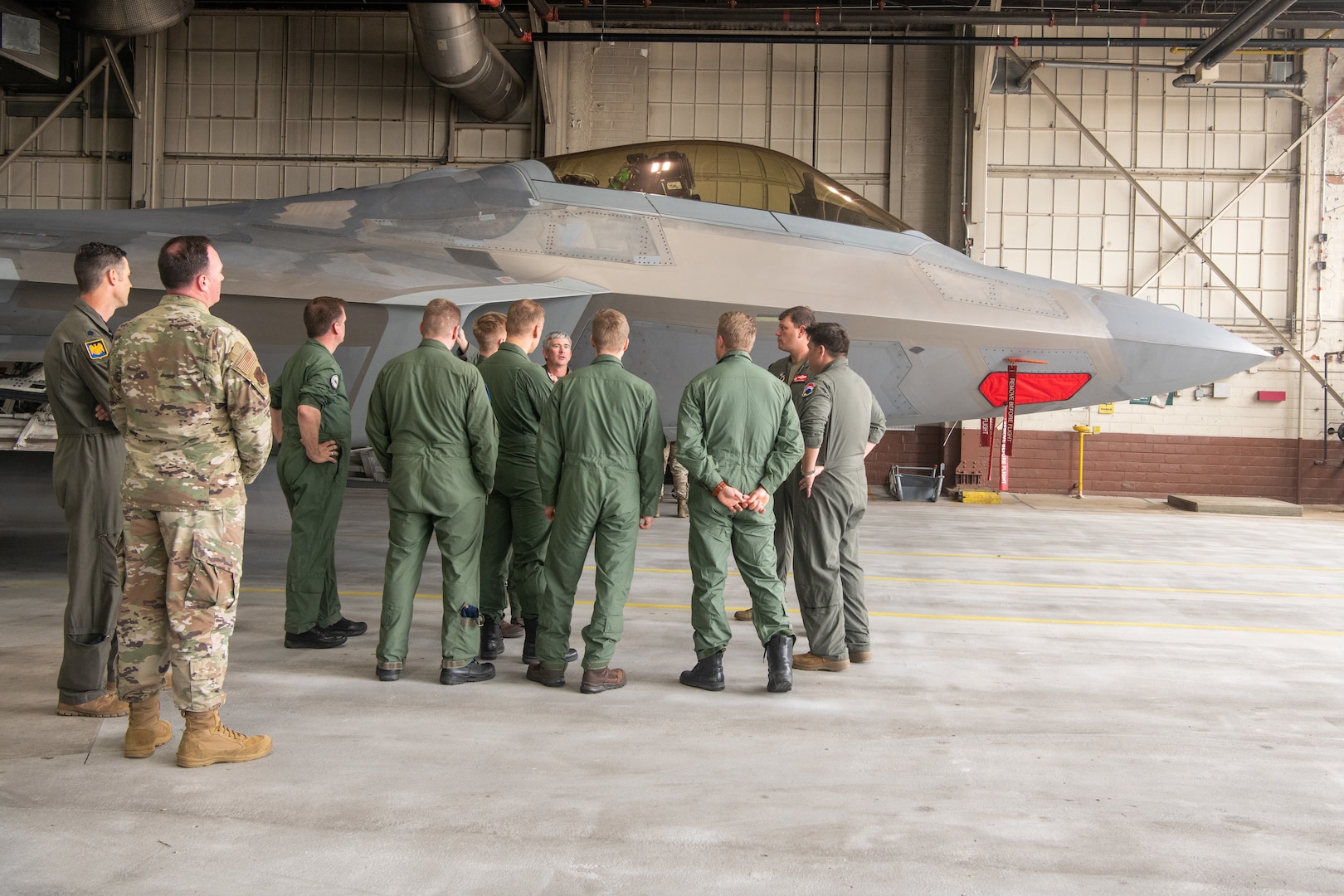 pilots talking around F-22 in hangar