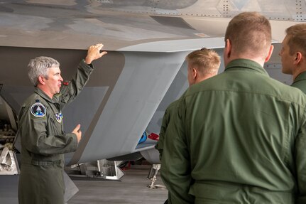 pilots talking around F-22 in hangar