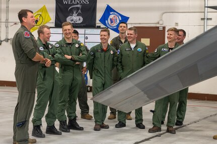 pilots talking around F-22 in hangar