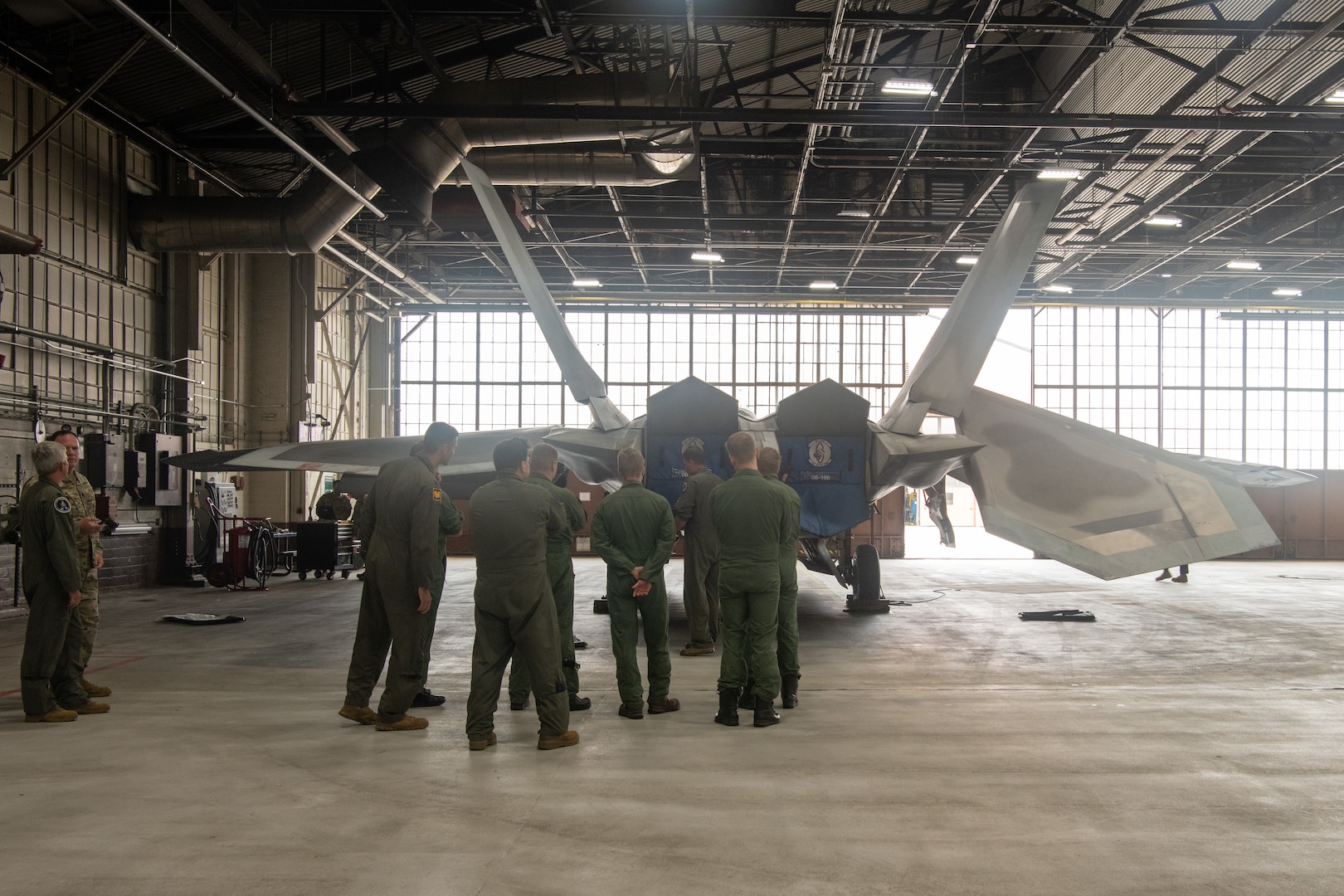 pilots talking around F-22 in hangar