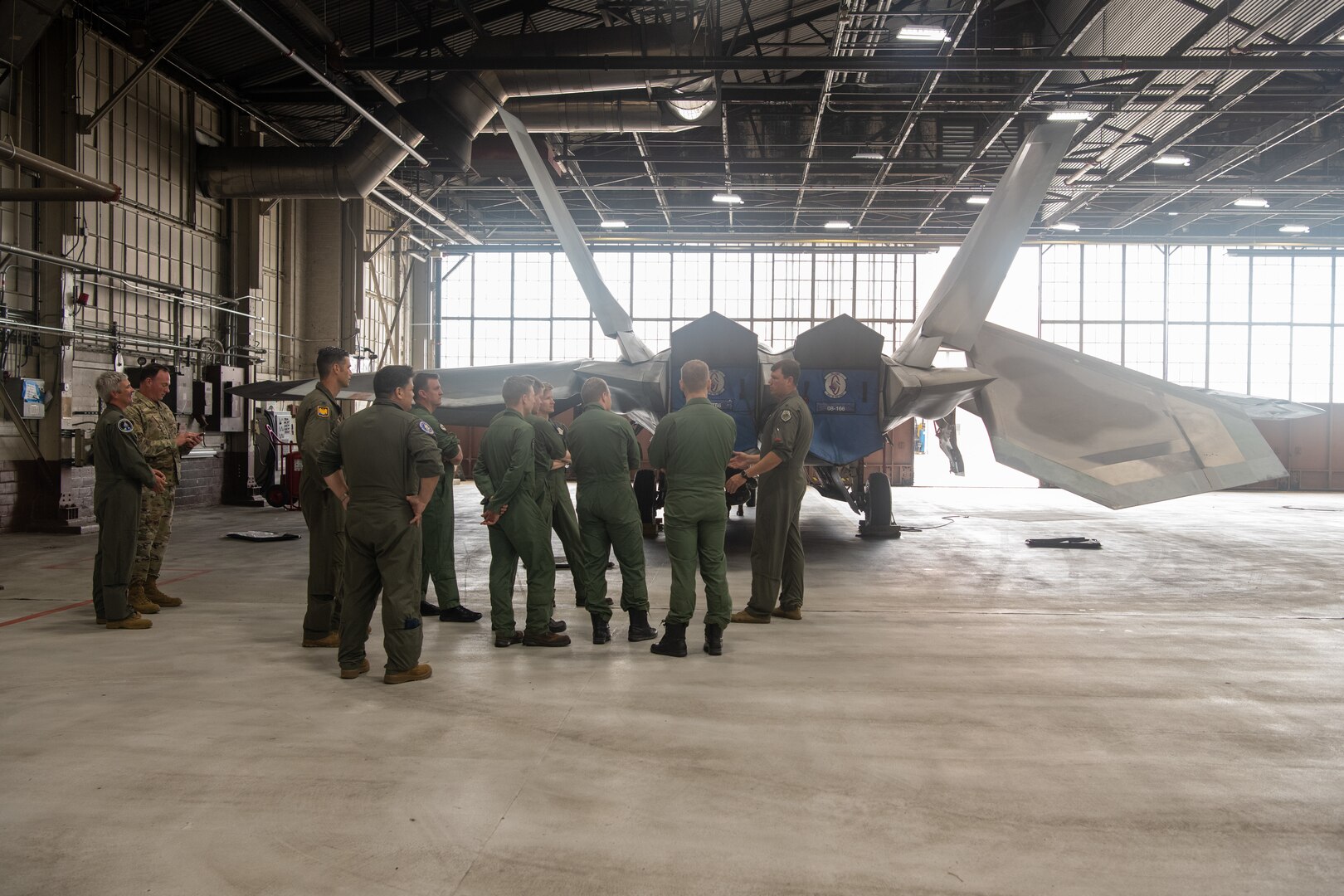 pilots talking around F-22 in hangar