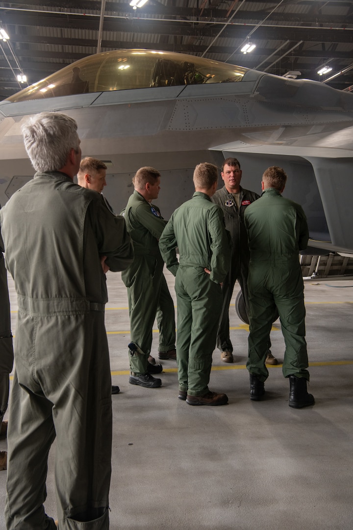 pilots talking around F-22 in hangar