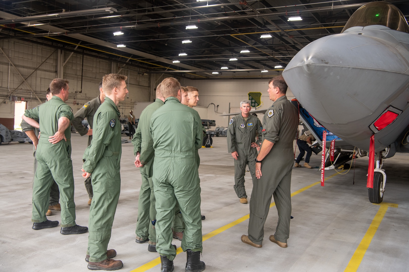 pilots talking around F-22 in hangar
