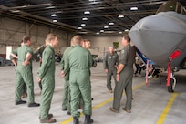 pilots talking around F-22 in hangar