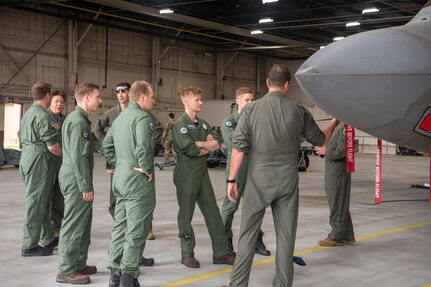 pilots talking around F-22 in hangar