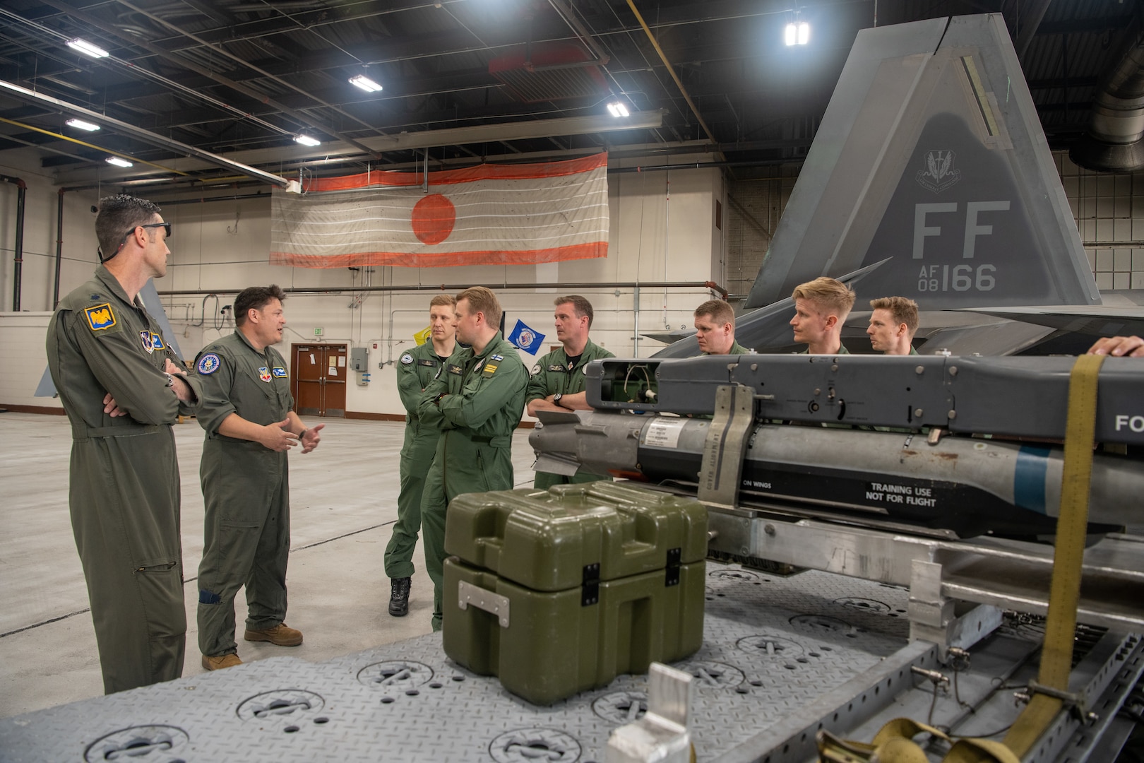 pilots talking around F-22 in hangar