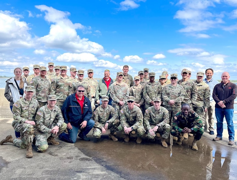 A group of soldiers in uniform pose with a blue sky in the background.