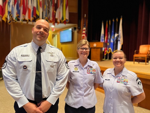 Photo of three senior noncommissioned officers in uniform standing and smiling at their graduation.