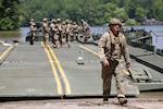 Army Staff Sgt. John Dennison, a platoon sergeant with the Kentucky National Guard’s 2061st Multi-Role Bridge Company, walks off the raft bridge onto the shore during the Homeland Defender Exercise at the Muscatatuck Training Center in Butlerville, Ind., June 9, 2023. Homeland Defender is a three-day, multi-agency exercise that brought together the Indiana National Guard, Kentucky National Guard, FEMA, Indiana first responders, and Verizon Communications.