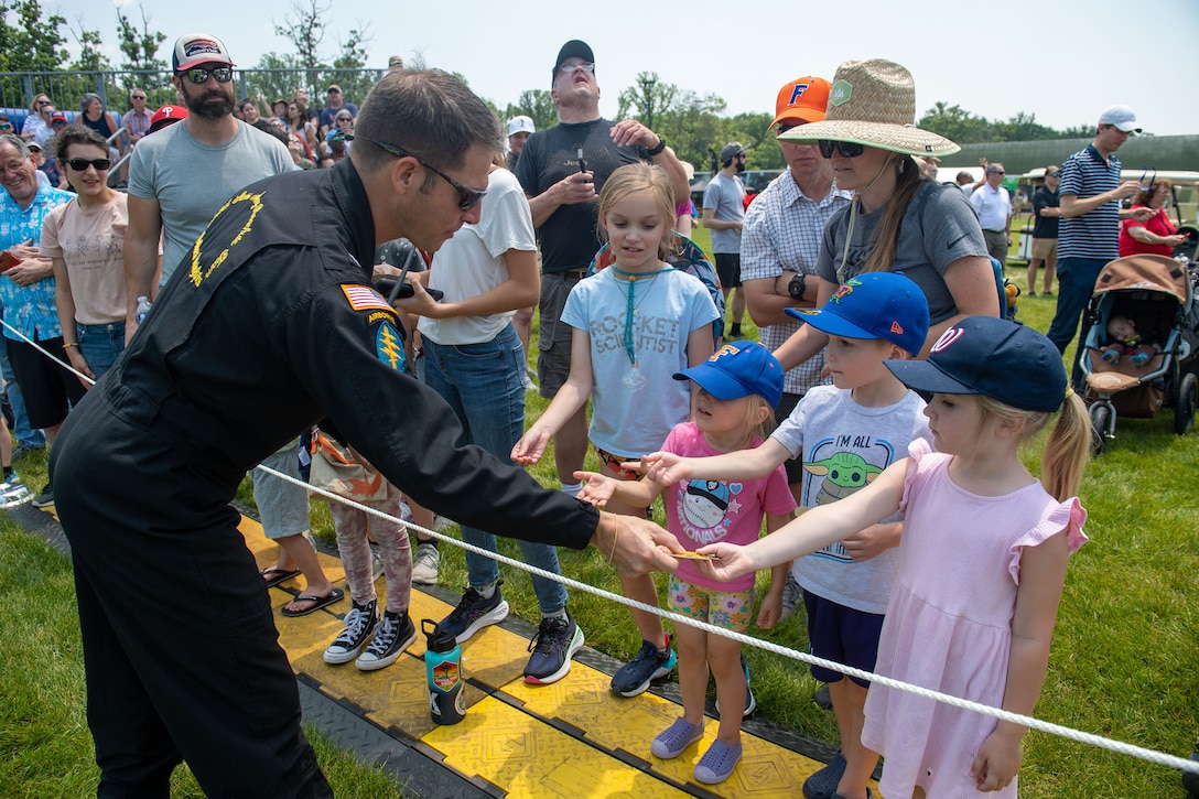 A service member hands out stickers to children.