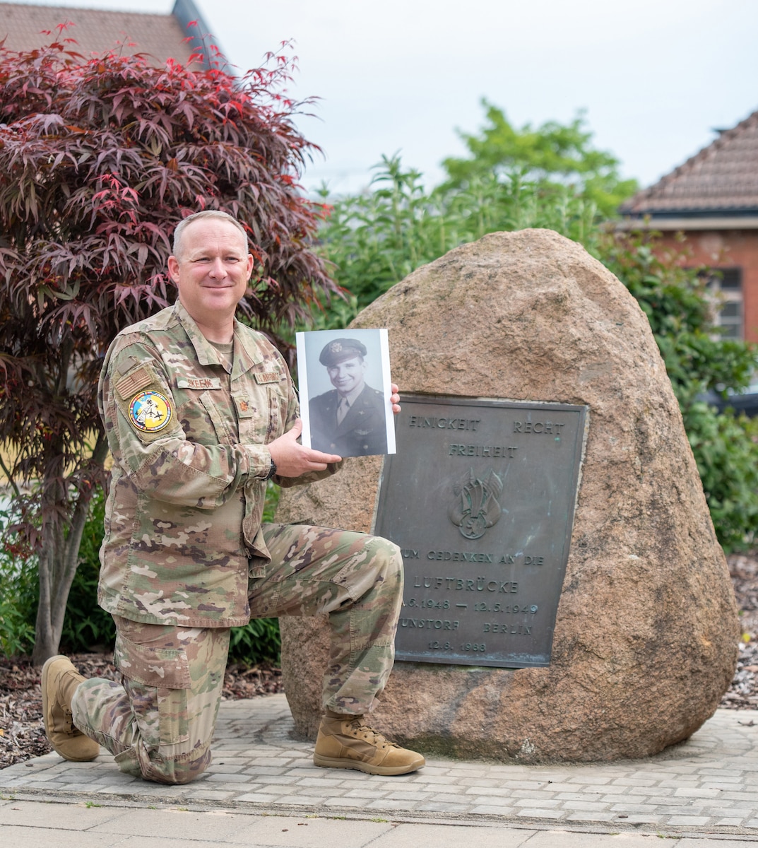 Maj. Matthew Skeens, a logistics readiness officer with the 123rd Contingency Response Element from Louisville, Kentucky, stands by a memorial on Wunstorf Air Base, Germany, June 7, 2023. The stone commemorates those who served in the famous Berlin Airlift. Skeens, who is deployed here in support of Exercise Air Defender 23, holds a picture of his grandfather, U.S. Air Force pilot Kenneth Skeens, who flew in that mission 75 years ago from this base. Exercise Air Defender integrates both U.S. and Allied air power to defend shared values, while leveraging and strengthening vital partnerships to deter aggression around the world. (U.S. Air National Guard photo by Senior Master Sgt. Vicky Spesard)