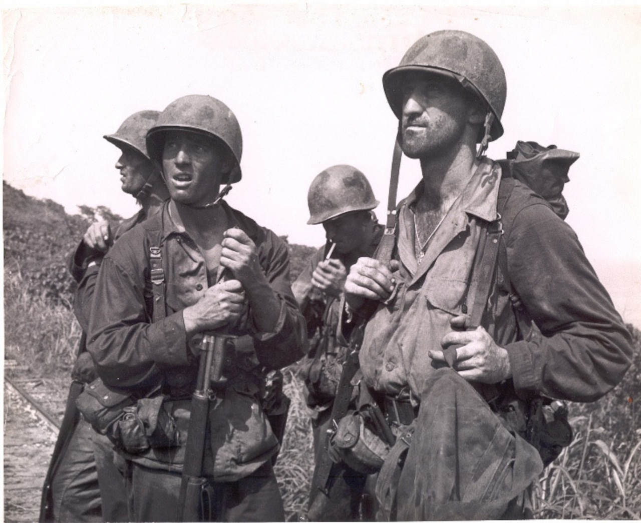 Four men in helmets look into the distance.