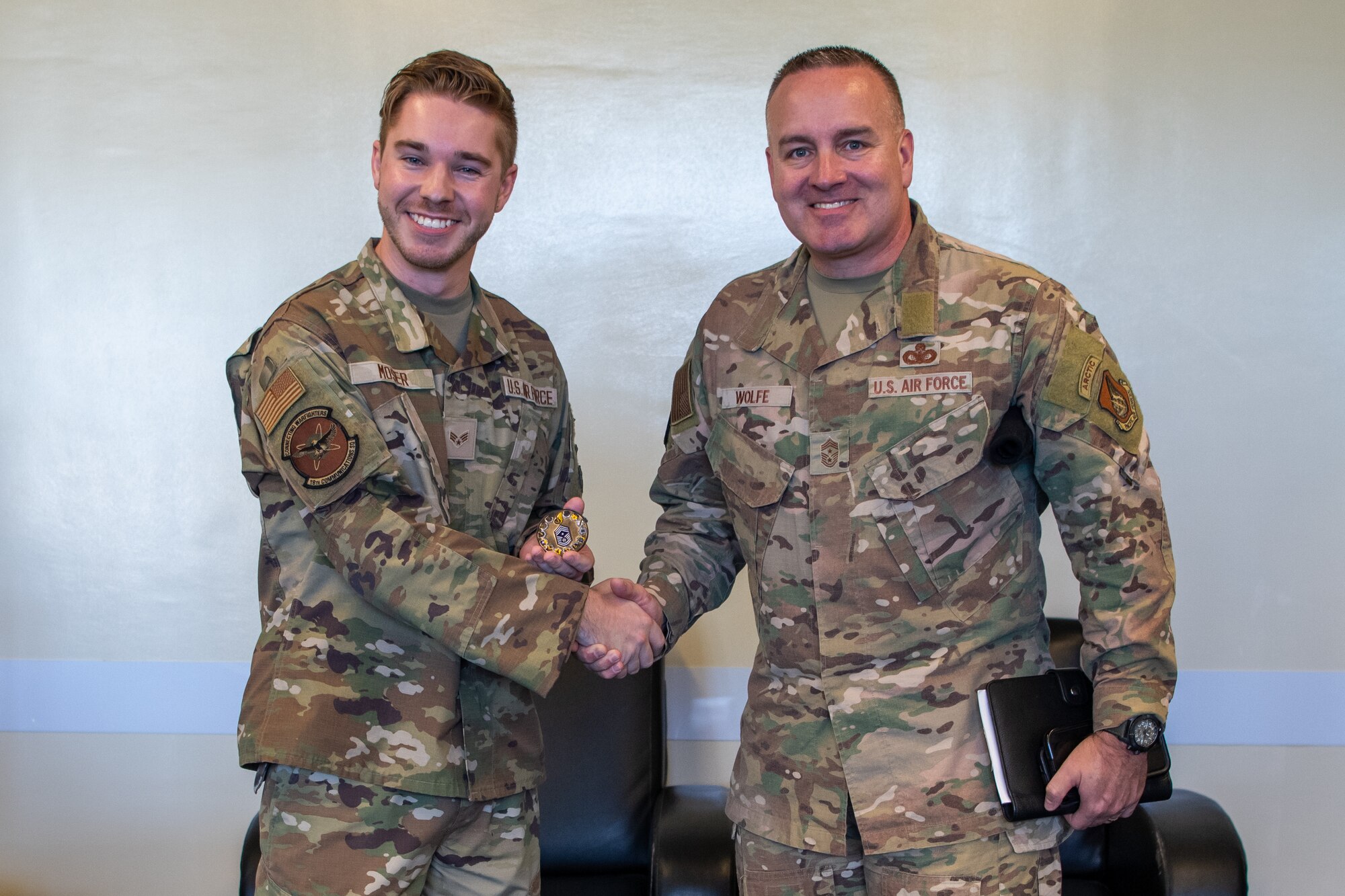 Two men pose with a coin.