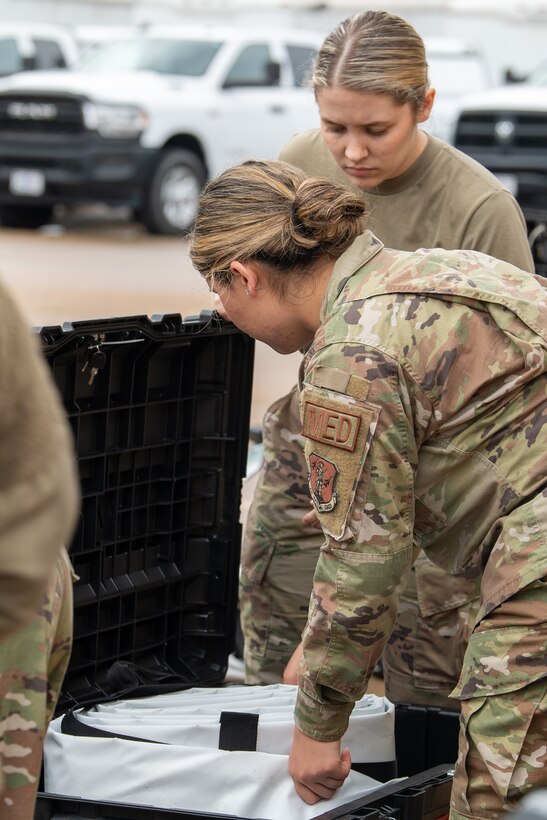 two Airmen pulling rolled up tent out of case