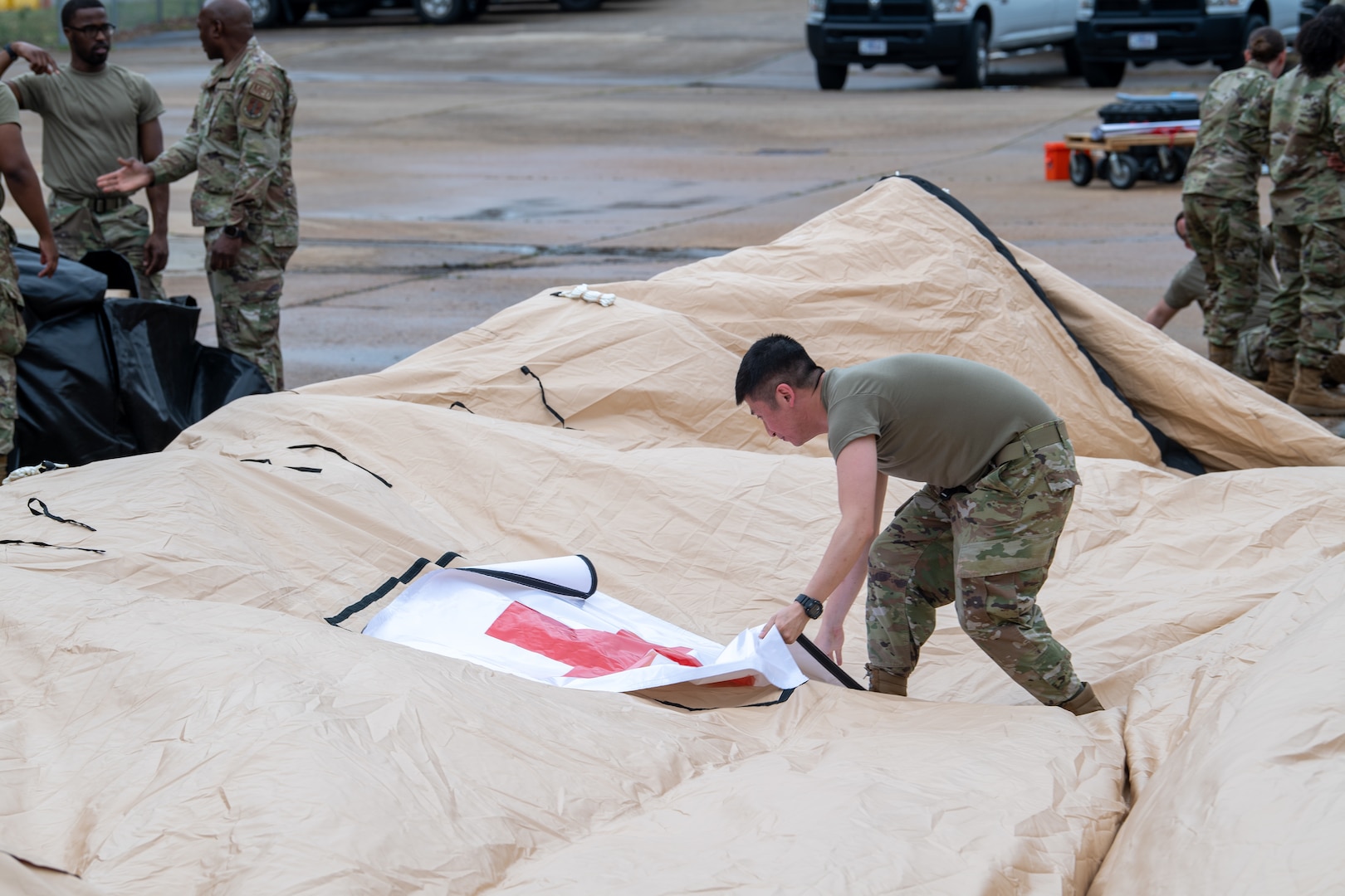 Airman standing on deflated tent fixing healthcare sign
