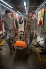 four Airmen carrying one Airman in gurney