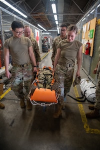 four Airmen carrying one Airman in gurney