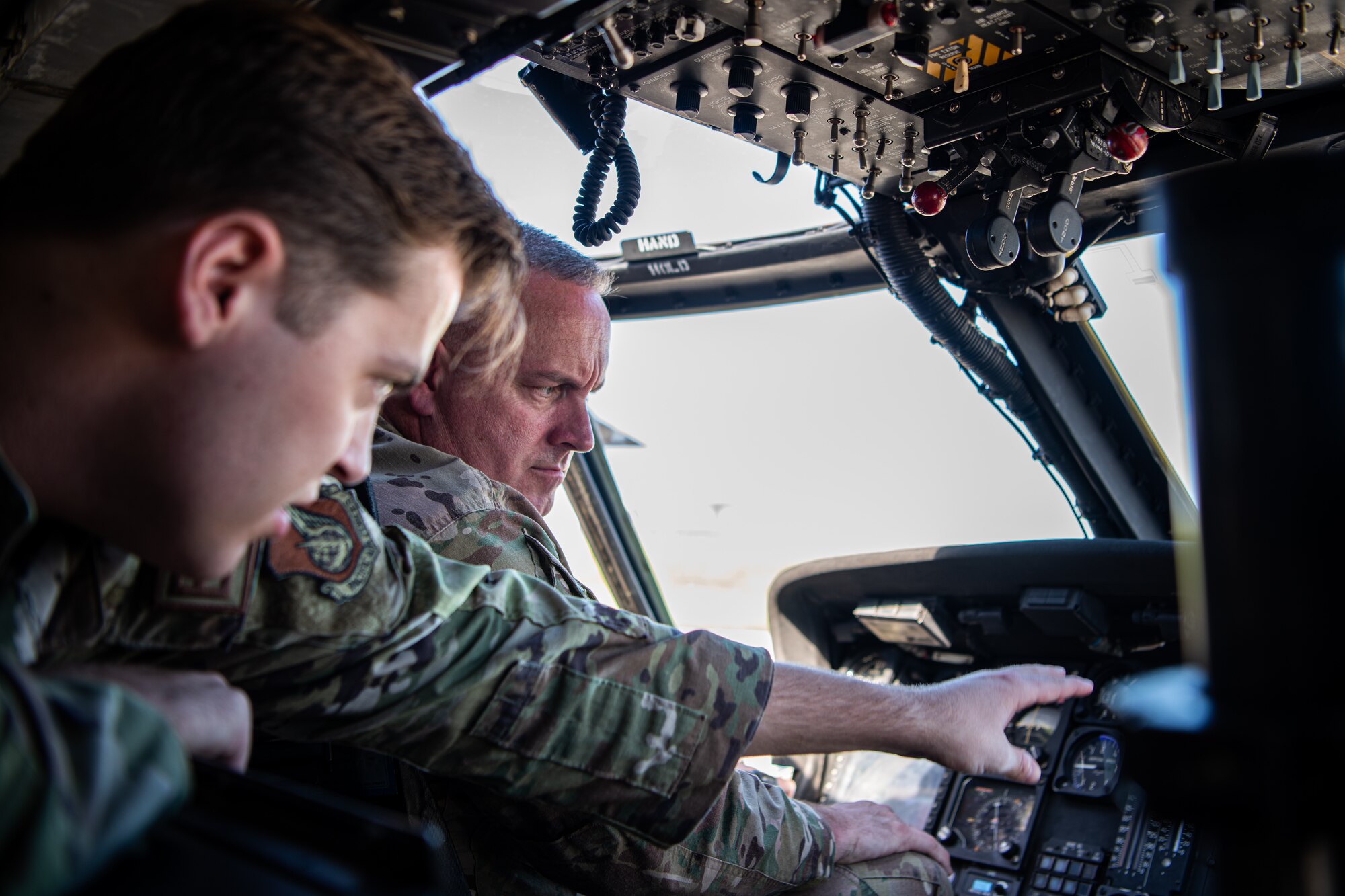 Two men look at helicopter components.