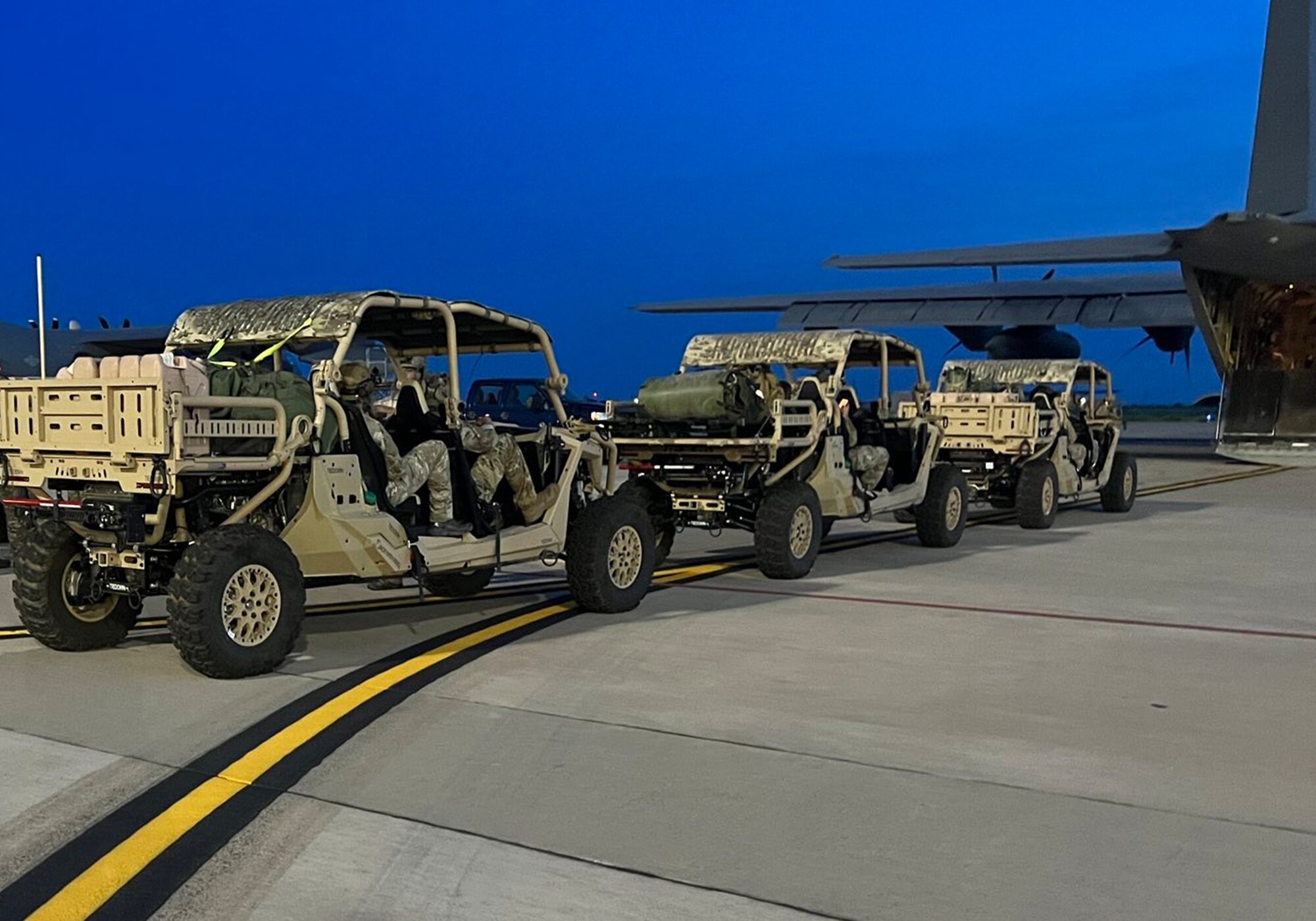 airmen drive all-terrain vehicles towards a cargo aircraft