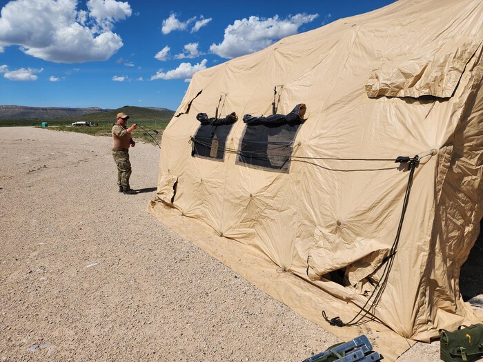 An Airman stands near a tent in a remote area