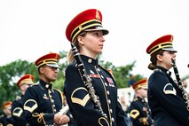 Band members wearing ceremonial uniforms stand in formation while holding instruments.