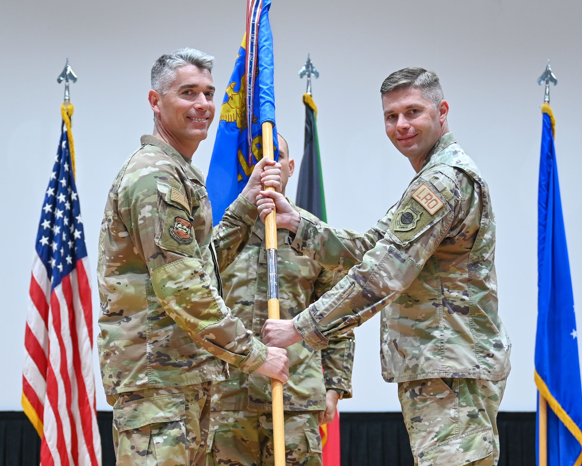 Maj. Shawn Cameron, outgoing 386th Expeditionary Logistics Readiness Squadron commander, passes the guidon to Col. George Buch, 386th Air Expeditionary Wing commander, during a change of command ceremony at Ali Al Salem Air Base, Kuwait, June 13, 2023. Cameron passed the guidon back to Buch as a symbol of relinquishing command of the unit. (U.S. Air Force photo by Staff Sgt. Breanna Diaz)