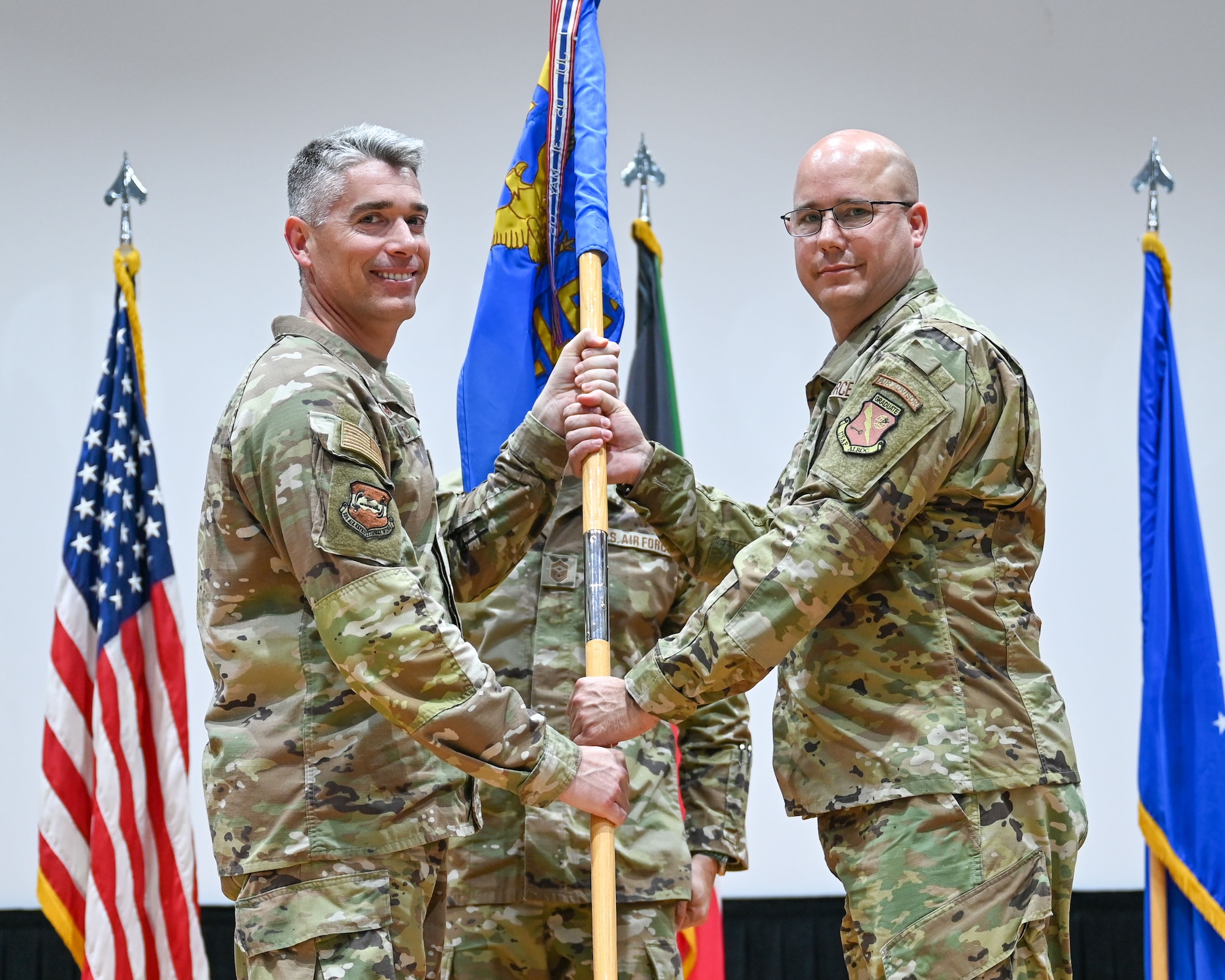 Col. George Buch, 386th Air Expeditionary Wing commander, passes the guidon to Maj. Marc Bleha, incoming 386th Expeditionary Logistics Readiness Squadron commander, during a change of command ceremony at Ali Al Salem Air Base, Kuwait, June 13, 2023. The passing of the guidon symbolizes the passing of command from one commander to the next. (U.S. Air Force photo by Staff Sgt. Breanna Diaz)